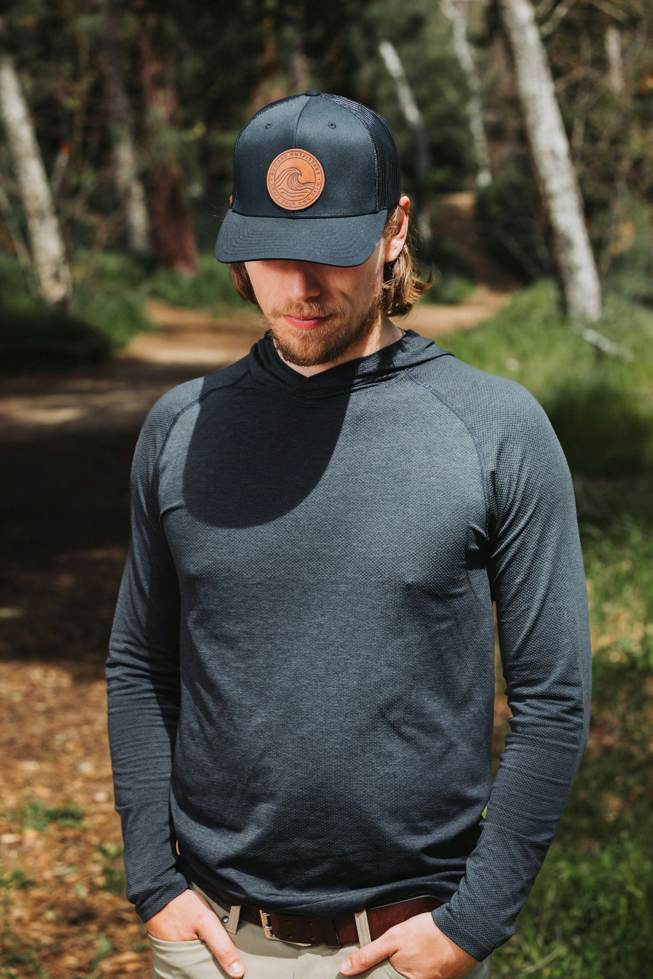 A man standing in the woods wearing a hat